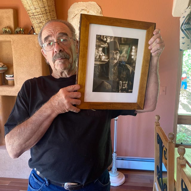A man proudly holding up his framed portrait